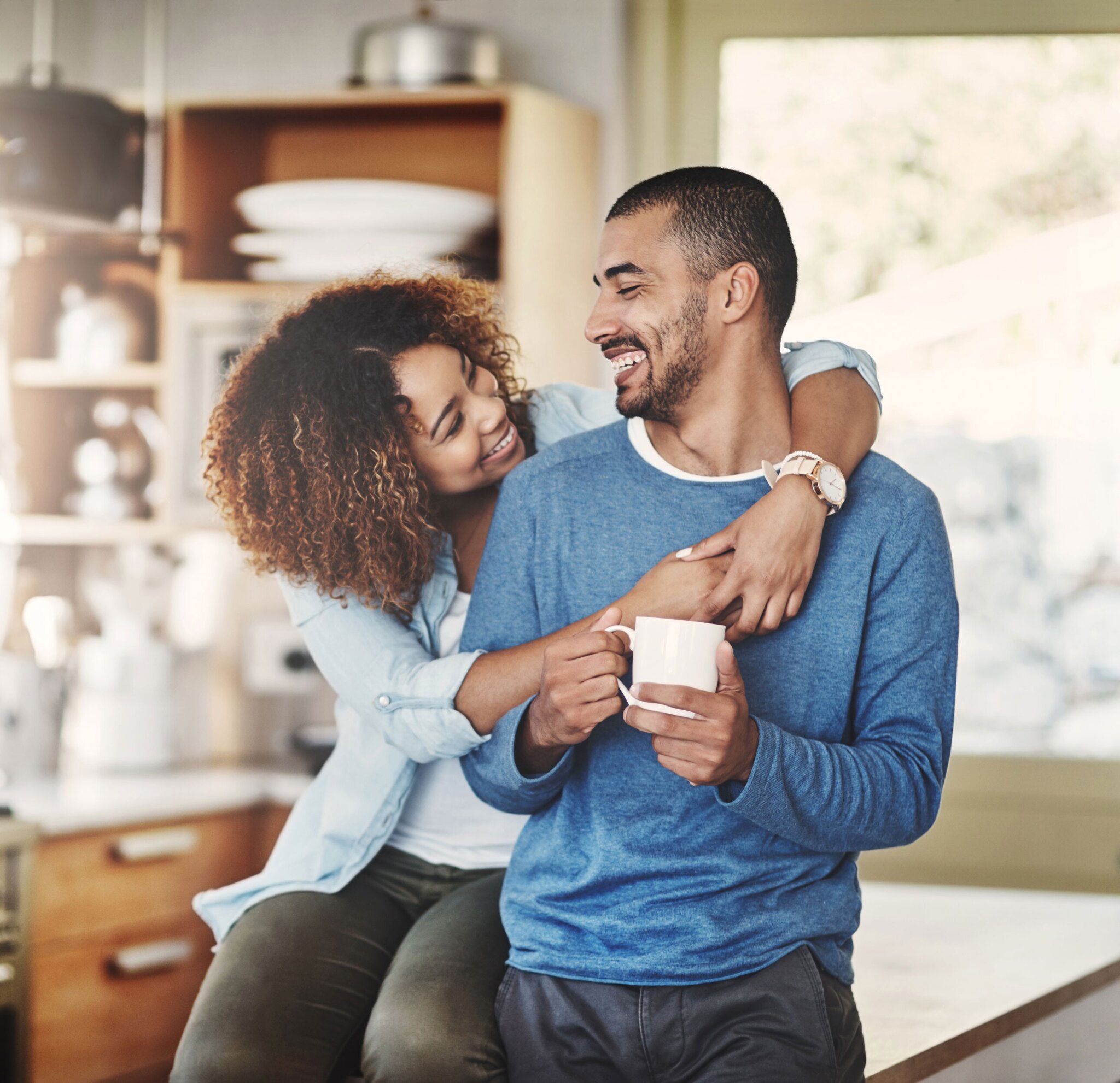 Couple sitting in their kitchen looking at eachother.