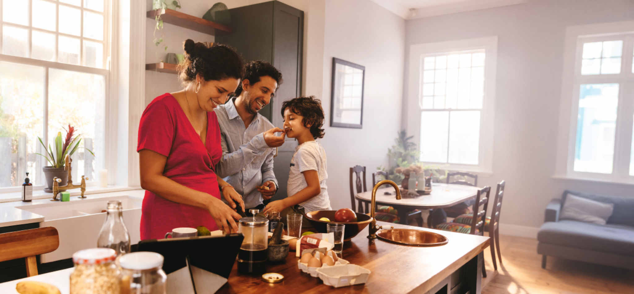 Family preparing food together in a kitchen, smiling and interacting.