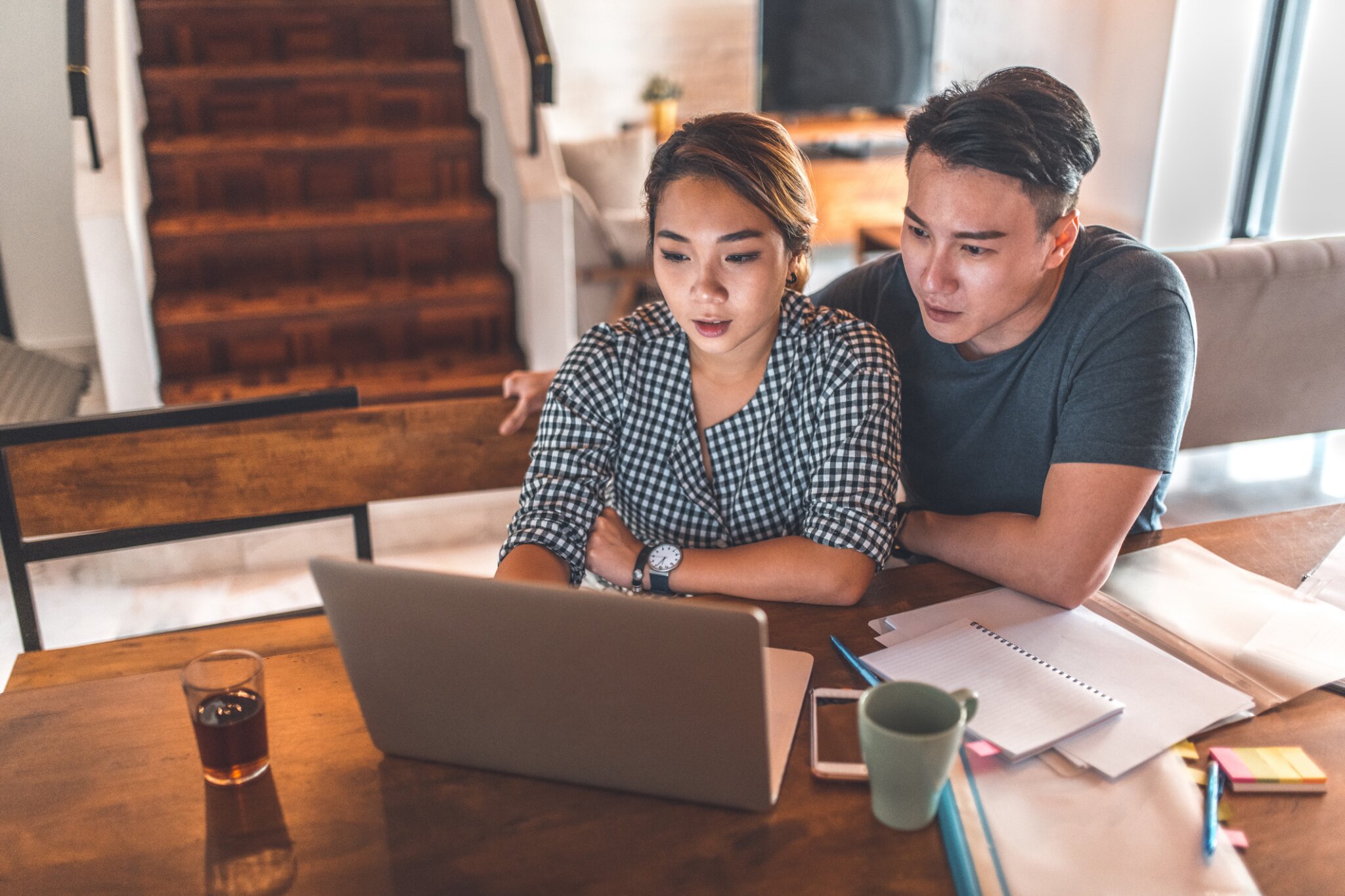 A couple sits at a desk collaborating on a laptop.