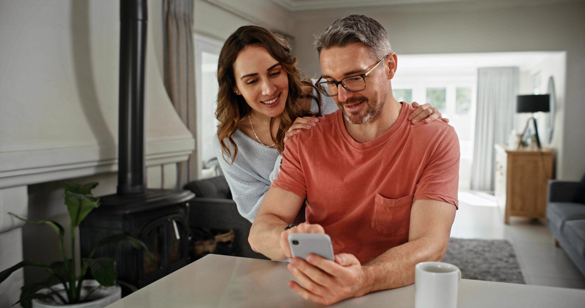 A man and woman look at a phone together while smiling.