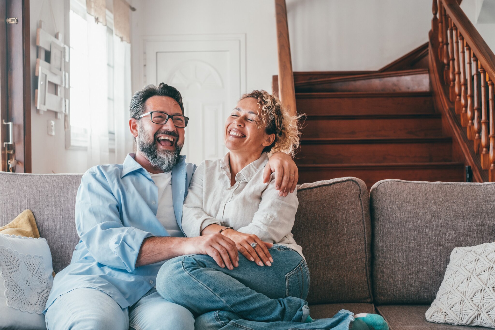 A couple embraces and laughs together on a sofa.