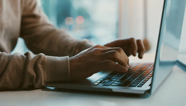 Hands type on a laptop computer.