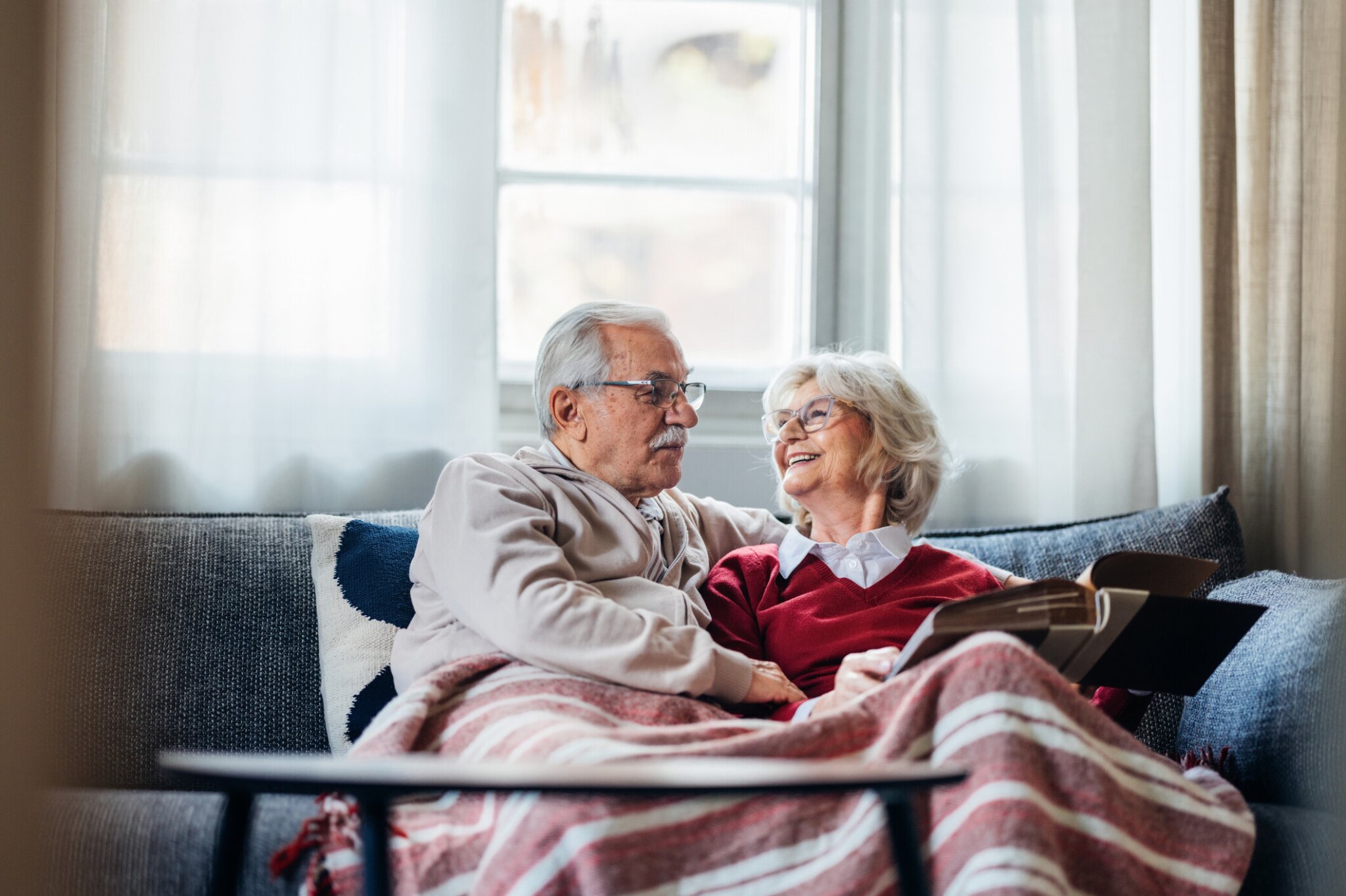 Older couple smiling on couch enjoying retirement thanks to saving using their rrsp.