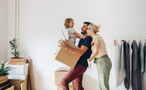 Family with a young child unpacking boxes together in a new home.