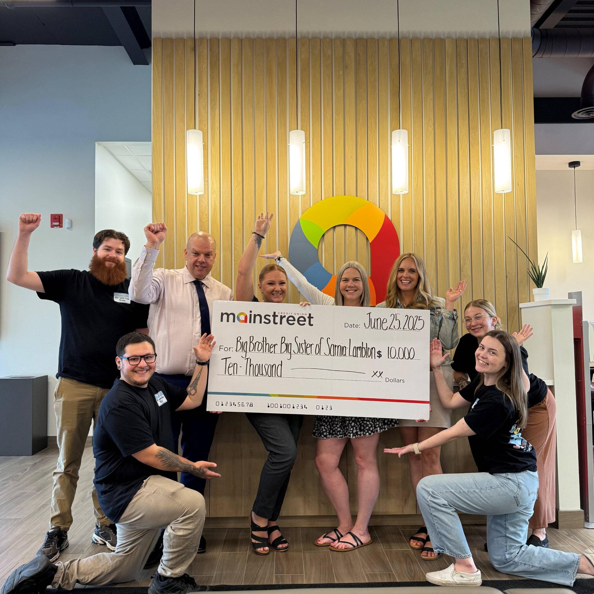 cheque donation photo at Mainstreet's Sarnia branch with staff and Big Brother's, Big Sisters Club staff smiling and cheering.