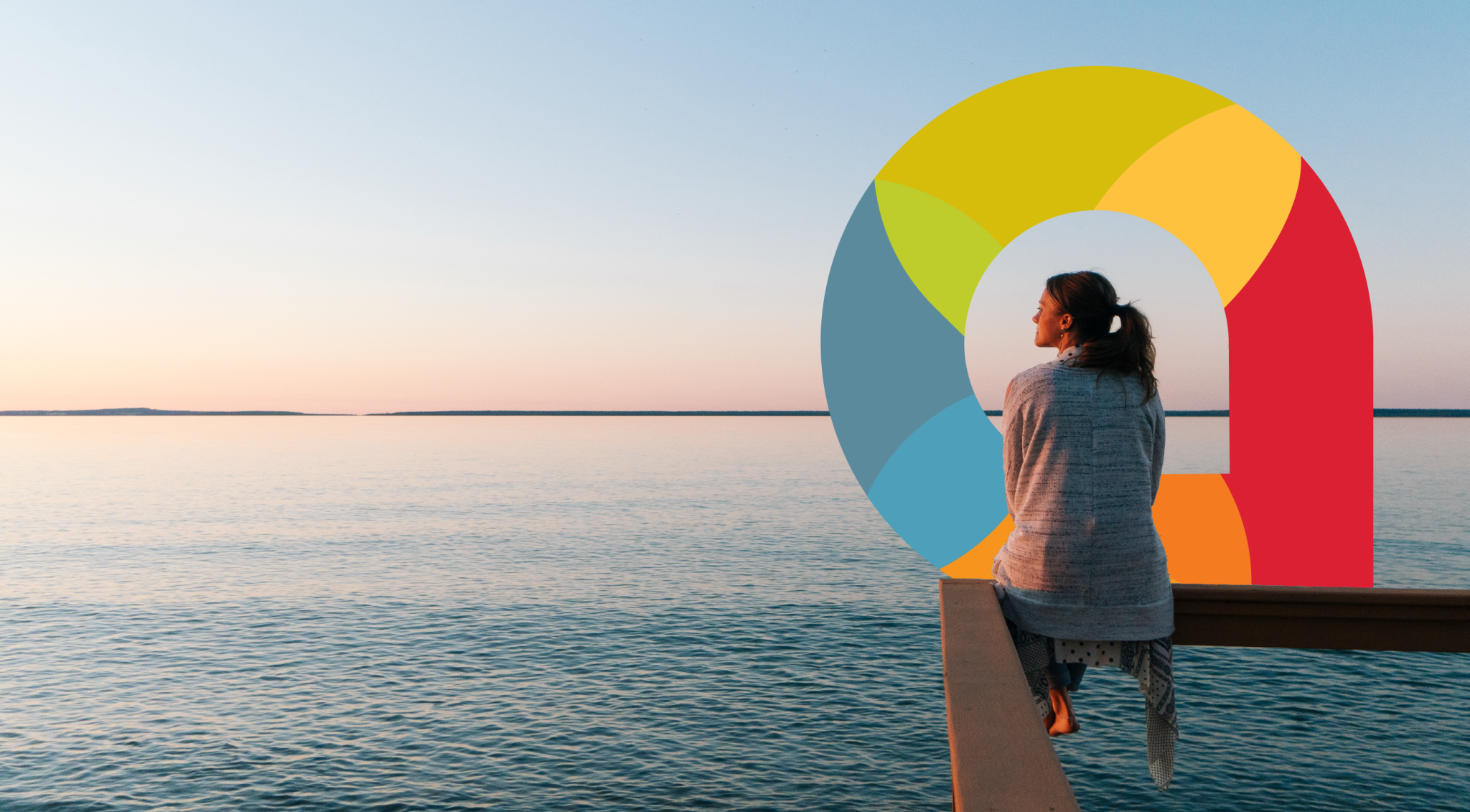 woman sitting on dock looking out at water.