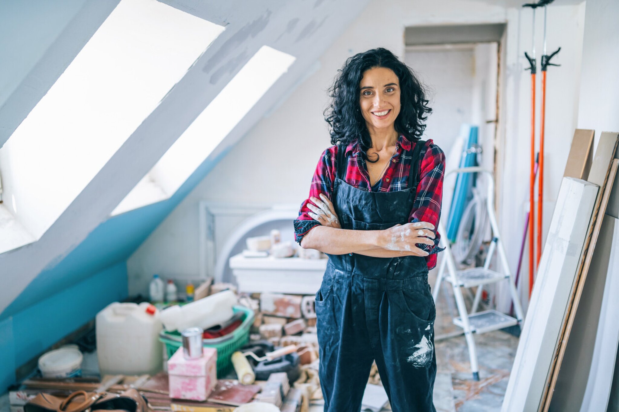 woman smiling standing with arms crossed in a room undergoing renovations.