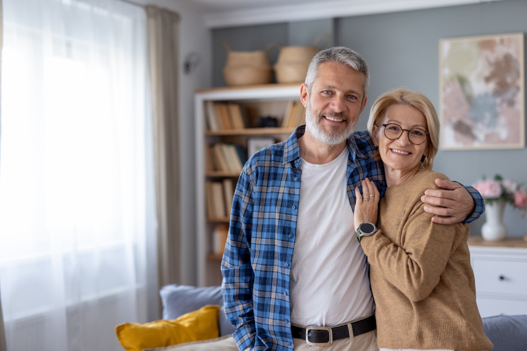 Older couple hugging and smiling in their living room.